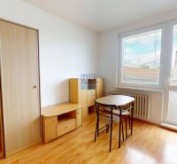 Na prenájom zariadená garsónka s balkónom v Holíči - Garsónka s nábytkom, stolom a stoličkami, podlaha s dreveným dekorom, veľké okno s žalúziami.