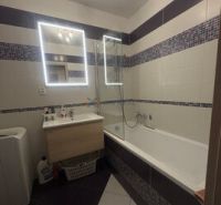 2 iz apartmán v príjemnej lokalite  - Kúpeľňa so zrkadlom a vaňou v 2-izbovom byte; biele obklady kombinované s mozaikou.