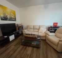 2 iz apartmán v príjemnej lokalite  - Obývacia izba 2-izbového bytu s podlahou s dreveným dekorom a pohodlným sedením.
