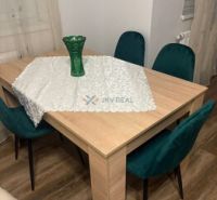 2 iz apartmán v príjemnej lokalite  - Jedálenský stôl s vázou a zelenými stoličkami, podlaha s dreveným dekorom v 2-izbovom byte.