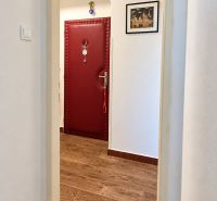 3-izbový byt v centre Pezinka, balkón, výťah, pivnica, komora - Chodba s červenými dverami a podlahou s dreveným dekorom v 3-izbovom byte.