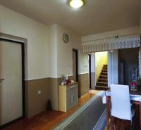 MIMORIADNE ZNÍŽENÁ CENA! Priestranný 6-izbový RD, Nenince, V. Krtíš. - Chodba v rodinnom dome s kobercovým schodiskom, stolom a podlahou s dreveným dekorom.