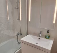 REZERVOVANÉ: 3 izbový byt + 2x balkón, komplet.rekonštr. - KOMÁRNO - Kúpeľňa v 3-izbovom byte s vaňou, zrkadlovou skrinkou a podlahou s dreveným dekorom.