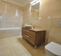 3-IZBOVÝ TEHLOVÝ BYT V DUBNICI NAD VÁHOM | 68 m² | BALKÓN | VLASTNÉ KÚ - Kúpeľňa v 3-izbovom byte s vaňou, umývadlom a skrinkou s dreveným dekorom.
