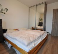 3-IZBOVÝ TEHLOVÝ BYT V DUBNICI NAD VÁHOM | 68 m² | BALKÓN | VLASTNÉ KÚ - Spálňa s posteľou, skriňou so zrkadlom a podlahou s dreveným dekorom v 3-izbovom byte.