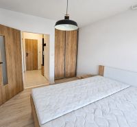 Na prenájom 2-izbový byt s balkónom v Bratislave– Rača - Spálňa v 2-izbovom byte s posteľou, skriňou a podlahou s dreveným dekorom.