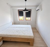 Na prenájom 2-izbový byt s balkónom v Bratislave– Rača - Spálňa s posteľou, klimatizáciou a podlahou s dreveným dekorom v 2-izbovom byte.