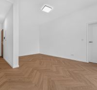 RADO I 3-izbový byt 59m² I Legionárska I Trenčianske Biskupice - Biely interiér 3-izbového bytu s podlahou s dreveným dekorom a moderným osvetlením.