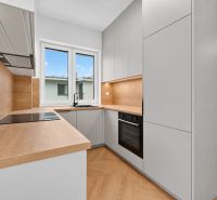 RADO I 3-izbový byt 59m² I Legionárska I Trenčianske Biskupice - Kuchyňa v 3-izbovom byte s podlahou s dreveným dekorom a modernými spotrebičmi.