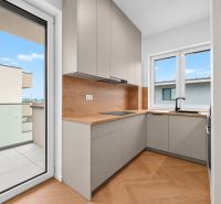 RADO I 3-izbový byt 59m² I Legionárska I Trenčianske Biskupice - Kuchyňa v 3-izbovom byte s podlahou s dreveným dekorom, výhľad na balkón.