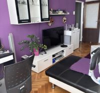 PREDAJ  2 izb. bytu s balkónom v Komárne - Obývacia izba v 2-izbovom byte so sedačkou a nábytkom, podlaha s dreveným dekorom.