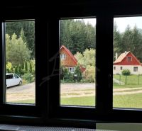 Zariadená chata s krbom pri lese v Rajeckej Lesnej - Výhľad na chaty v Rajeckej Lesnej, obklopené zeleňou a autami.