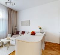 Palisády - staromestský nadštandardne rekonštruovaný byt - Svetlá obývacia izba s kuchyňou, bielym nábytkom a dekoráciami na ulici Flöglova.