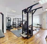 RIVERS | Nebytový priestor v Dúbravke na predaj - Posilňovňa s rôznym fitness vybavením a podlahou s dreveným dekorom v obchodných priestoroch.
