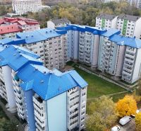 RIVERS | Nebytový priestor v Dúbravke na predaj - Panelové domy s modrými strechami na Agátovej ulici, Bratislava - Dúbravka, obklopené stromami.