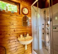 Predaj chaty a chalupy Banská Štiavnica - Kúpeľňa v rodinnom dome s dreveným obložením, sprchovacím kútom a oknom.