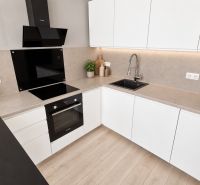 Moderný 2-izbový apartmán, balkón, sklad, Šancová-novostavba PREMIÈRE - Kuchyňa v 2-izbovom byte s bielymi skrinkami, varnou doskou a podlahou s dreveným dekorom.