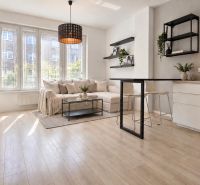 Moderný 2-izbový apartmán, balkón, sklad, Šancová-novostavba PREMIÈRE - Obývacia izba s kuchyňou, sedacou súpravou a podlahou s dreveným dekorom v 2-izbovom byte.