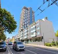Moderný 2-izbový apartmán, balkón, sklad, Šancová-novostavba PREMIÈRE - Šancová ulica v Bratislave - Staré Mesto s modernou výškovou budovou a zeleňou.