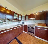 3.izbový byt so záhradou /420 m²/ a chatkou BOŠANY - Kuchyňa v 3-izbovom byte s tmavými skriňami a podlahou s dreveným dekorom.