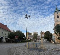 Lukratívny obchodný priestor v Centre Topolčian   - Obchodné priestory v Topoľčanoch s dláždeným námestím a kostolom v pozadí.