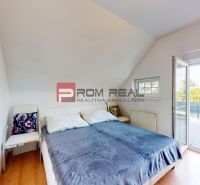 3D OBHLIADKA -  Veľký 2-izbový podkrovný byt s rozlohou 62 m2 + terasa - Svetlá spálňa s posteľou a stoličkou, 2-izbový byt s dreveným dekorom podlahy.