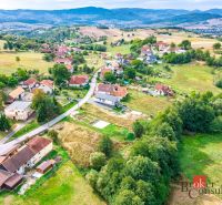 Pozemok na predaj v Detve, Skliarovo, aj so základovou platňou - Letecký pohľad na obytné pozemky v meste Detva s okolitou prírodou a budovami.