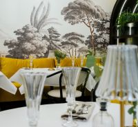 Jedinečná príležitosť - reštaurácia s kompletným konceptom a zázemím - Interiér s elegantnými stolmi, pohármi a kreslenou krajinou na stene, obchodné priestory.