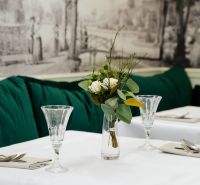 Jedinečná príležitosť - reštaurácia s kompletným konceptom a zázemím - Elegantne prestretý stôl s bielym obrusom, vázou s kvetmi a krištáľovými pohármi.