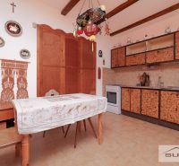 Starší rodinný dom s veľkou záhradou v obci Štefanová | okres Pezinok - Kuchyňa v rodinnom dome s rustikálnym dekorom a nástennými dekoráciami nad stolom.
