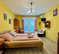 NA PREDAJ apartmán v Podhájskej  - Interiér s posteľou, stoličkami a podlahou s dreveným dekorom v Rekreačnom apartmáne.