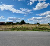 NA PREDAJ Stavebný pozemok v obci Golianovo - Stavebný pozemok na bývanie v Golianove, plný zelene a modrej oblohy.