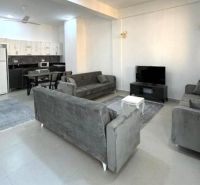 2-IZBOVÝ CONDO APARTMÁN PRI PLÁŽI, MBWENI, ZANZIBAR - Moderná obývačka v 2-izbovom byte s veľkou sedacou súpravou a kuchynským kútom.