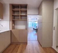 Na predaj úplne nový 1i byt od architekta v tichej časti Dúbravky - Kuchyňa v 1-izbovom byte s podlahou s dreveným dekorom a úložnými priestormi.