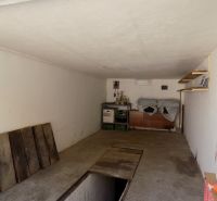 Nadštandardne vybavená garáž s pivnicou a studňou v Štúrove - Garáž s policami, cestnou podlahou, regálmi a uloženými predmetmi.