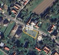Rovinatý Pozemok určený k výstavbe domu - Letecký pohľad na pozemok na bývanie v Moravskom Lieskovom s viditeľnou ulicou a budovami.