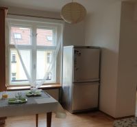 Praktický byt v širšom centre neďaleko Trnavského Mýta. Mestská ul.  - Kuchynský kút v 2-izbovom byte s chladničkou a jedálenským stolom, podlaha s dreveným dekorom.