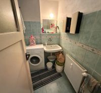 Na predaj 3i byt Levice, 73m2 - Kúpeľňa so svetlomodrými obkladmi obsahuje umývadlo a práčku v 3-izbovom byte.