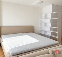 Luxusný 1 izbový byt s parkovacím miestom za luxusnú cenu - Spálňa v 1-izbovom byte s posteľou a bielymi policami, podlaha s dreveným dekorom.