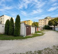 PRENÁJOM - Murovaná garáž 18 m² –  Nitra - Garáže na Schurmannovej ulici v Nitre s obytnými domami a modrou oblohou.