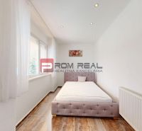 6i DVOJGENERAČNÝ DOM PO REKONŠTRUKCII S VEĽKÝM POZEMKOM A SMARTHOME –  - Spálňa v Rodinnom dome s posteľou, oknom a podlahou s dreveným dekorom.