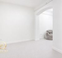 **Hotový priestor. Povolené ubytovanie. Pripravené zarábať**Airbnb** - Biela izba s kobercovou podlahou a sivým vakom na sedenie.