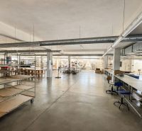 NA PREDAJ MODERNÝ VÝROBNO-SKLADOVACÍ AREÁL V SNINE - Priestranné obchodné priestory s minimalistickým zariadením a kovovými regálmi.
