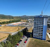Na predaj 3 izbový byt Žiar nad Hronom, 75 m2 - Pohľad na panelový dom a obchodné centrum na ulici SNP, Žiar nad Hronom.