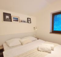 3 - IZBOVÝ APARTMÁN POD CHOPKOM, 52M2 - Spálňa v rekreačnom apartmáne s manželskou posteľou, dekoráciami a veľkým oknom.