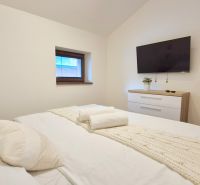 3 - IZBOVÝ APARTMÁN POD CHOPKOM, 52M2 - Spálňa v rekreačnom apartmáne s pohodlnou posteľou, televízorom a komodou.