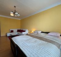 Na predaj: 2 izbový byt + PIVNICA + ŠPAJZA - Spálňa 2-izbového bytu so žltými stenami, sedačkou a podlahou s dreveným dekorom.