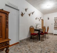 I VILA REIM – Exkluzívna investičná príležitosť  - Interiér chaty s kamennou podlahou, loveckými trofejami a vyrezávanou drevenou skriňou.