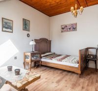 I VILA REIM – Exkluzívna investičná príležitosť  - Interiér chaty s dreveným dekorom podlahy, jednoduchá posteľ a starožitné kreslo.