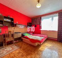 Priestranný 5-izbový rodinný dom na veľkom pozemku pri lese - Interiér rodinného domu s červenými stenami, stolom, posteľou a podlahou s dreveným dekorom.